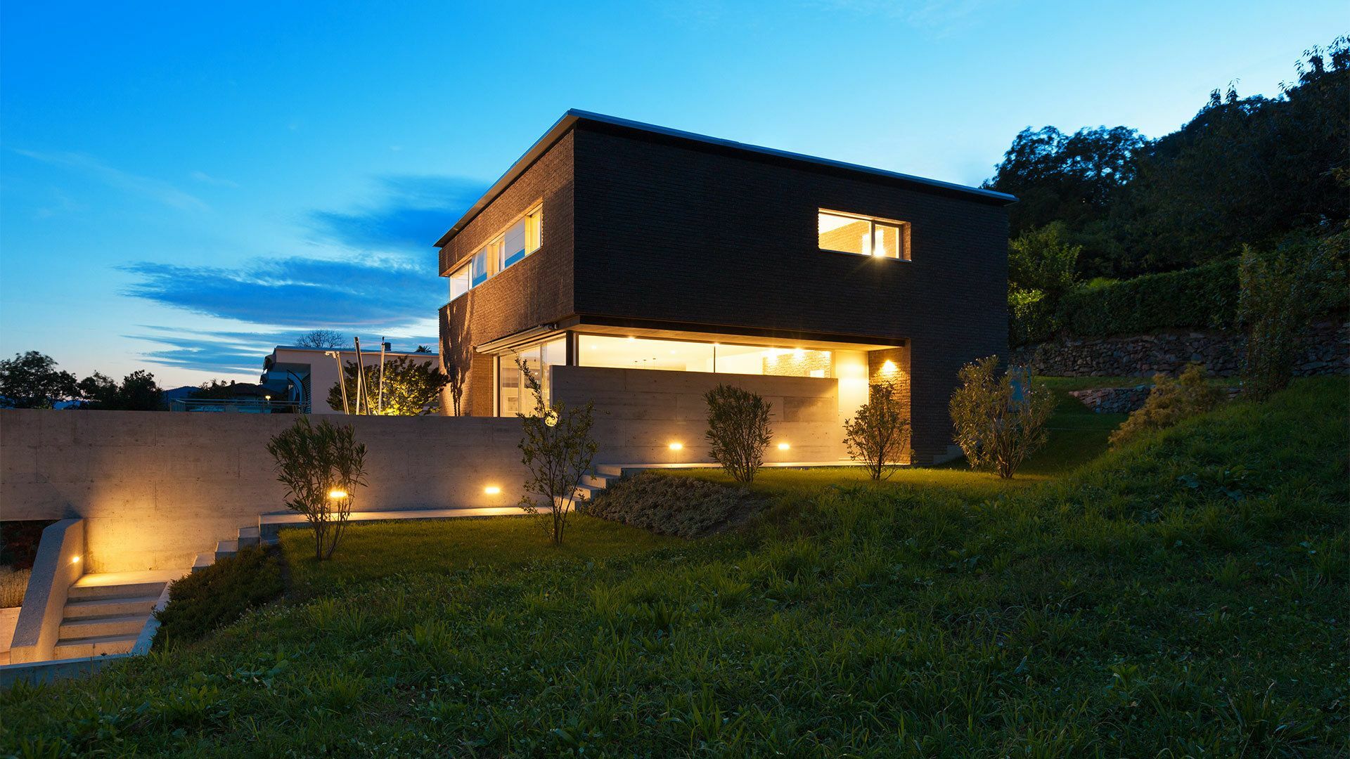 Modernes Einfamilienhaus am Abend mit effektvoller Innen- und Au&szlig;enbeleuchtung